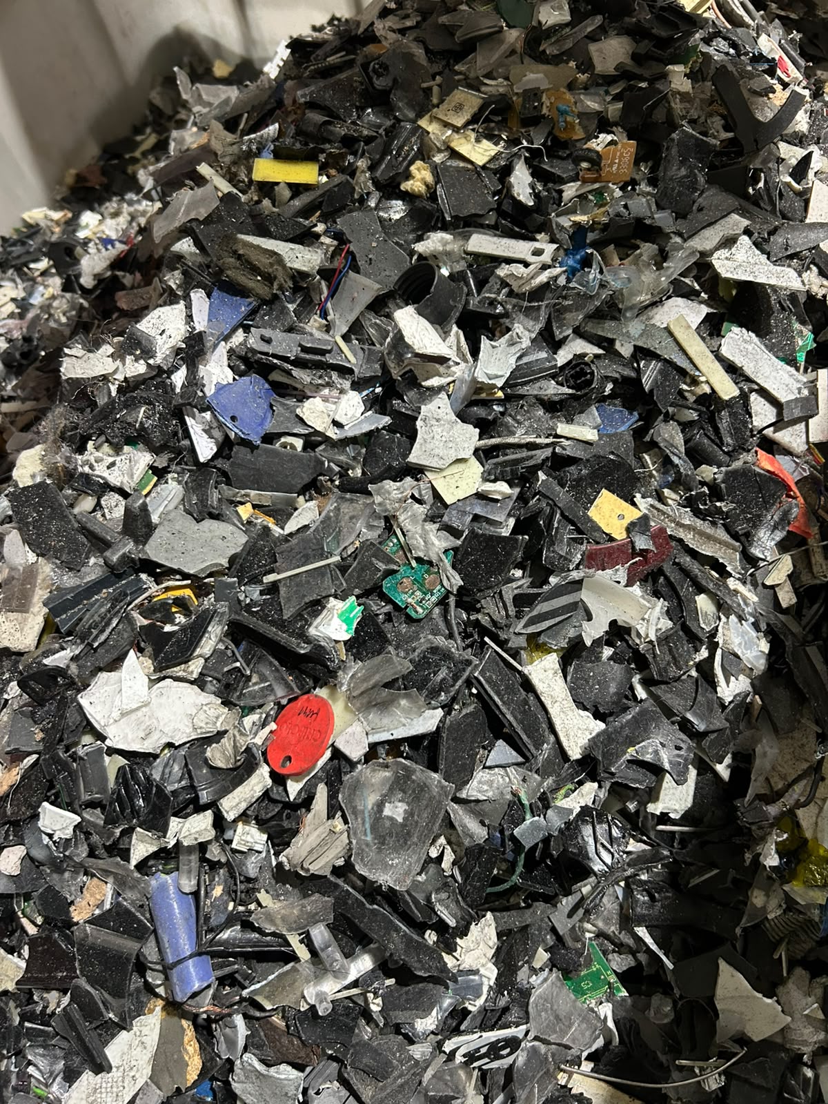 Original shredded material with mixed black, grey, and coloured fragments